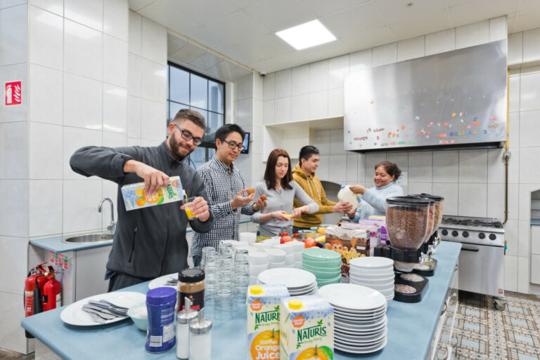 Travellers preparing a meal around the kitchen at Canbe Hostels - Gardiner House