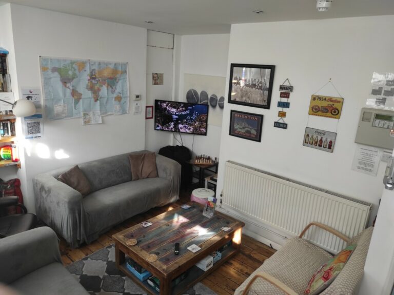 Living Room with couch, chairs, table and a map on the wall in Seadragon Backpackers Hostel