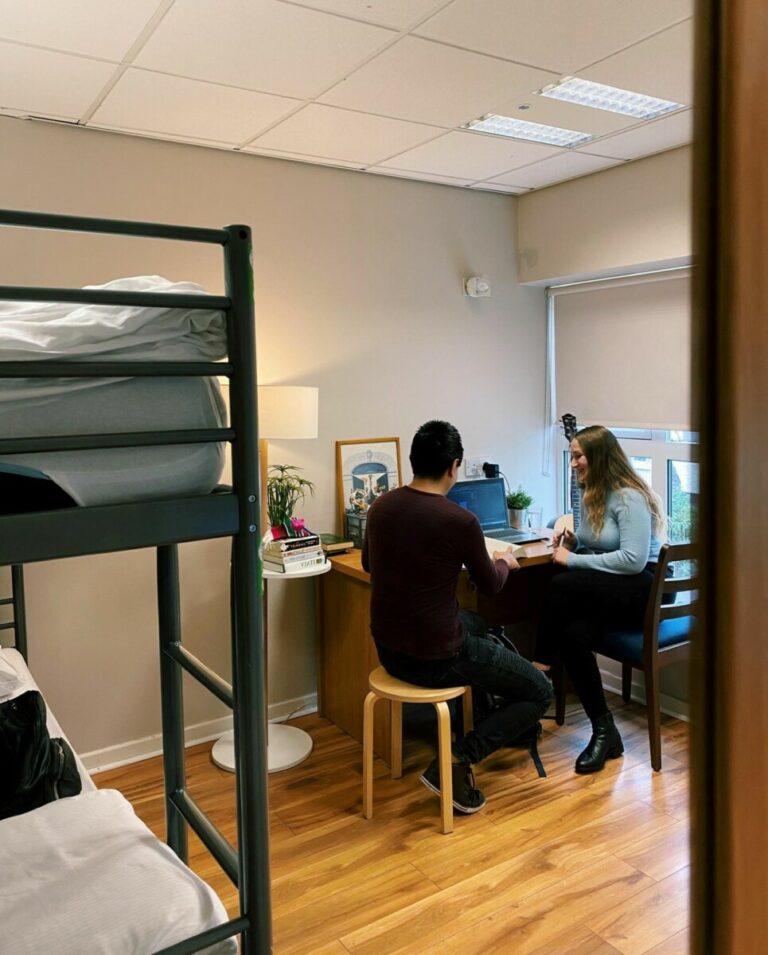 View of room with bunk bed in foreground and guests in background at Canbe Hostels - Garden Lane