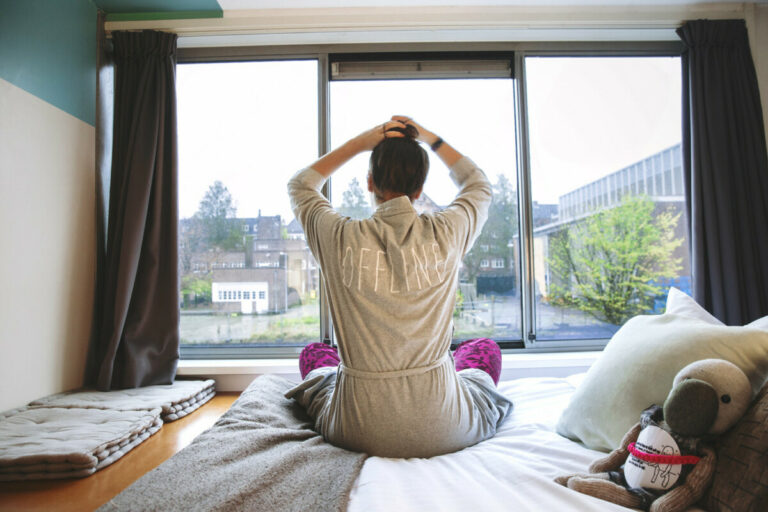 Guest waking up and looking out glass window at Ecomama Hostel in Amsterdam